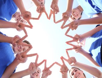 Team of volunteers putting their hands together as symbol of unity, bottom view